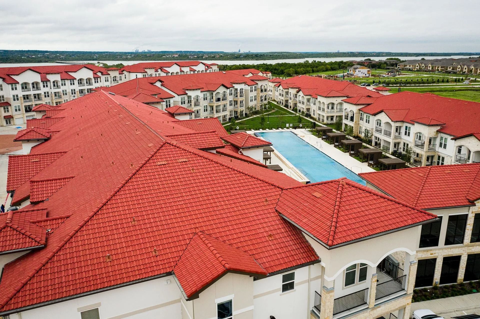 Aerial view of a resort with red-tiled roofs and a central blue swimming pool