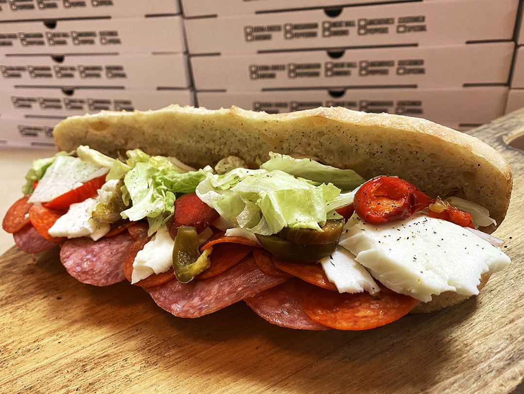 A sub sandwich is sitting on a wooden cutting board.