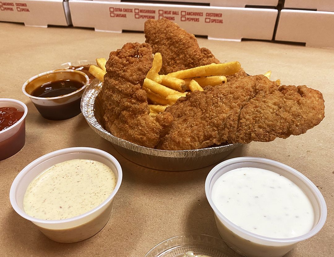 A plate of fried chicken and french fries with dipping sauces on a table.