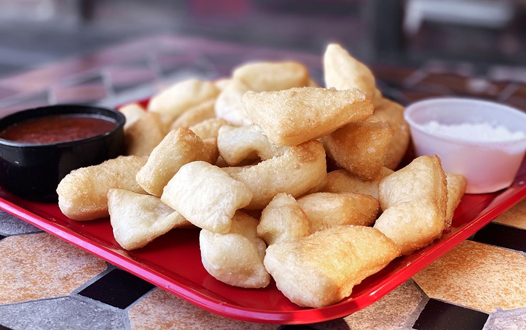 A red tray filled with fried food and dipping sauce on a table.