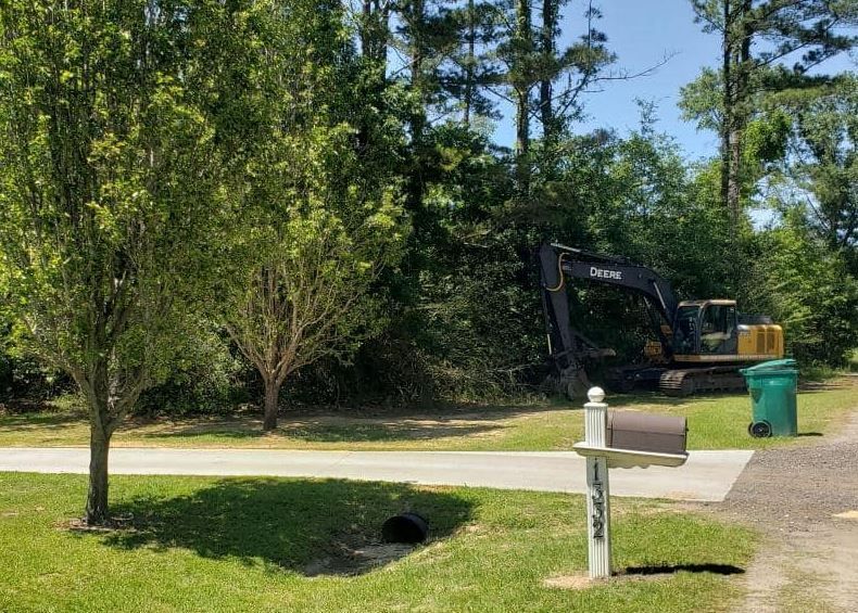 A large excavator is parked on the side of the road next to a mailbox.