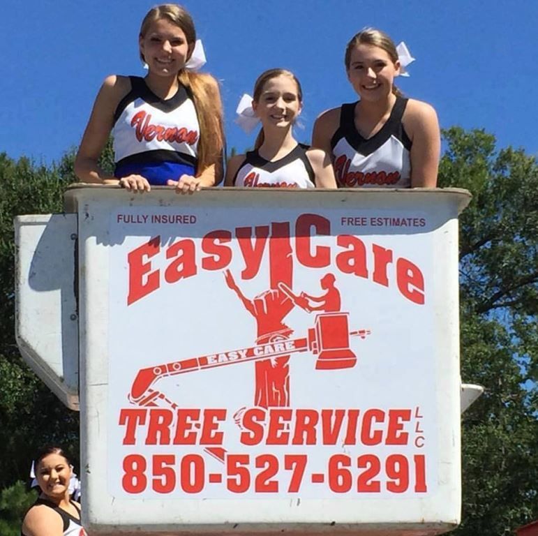 A group of cheerleaders standing on top of an easy care tree service truck