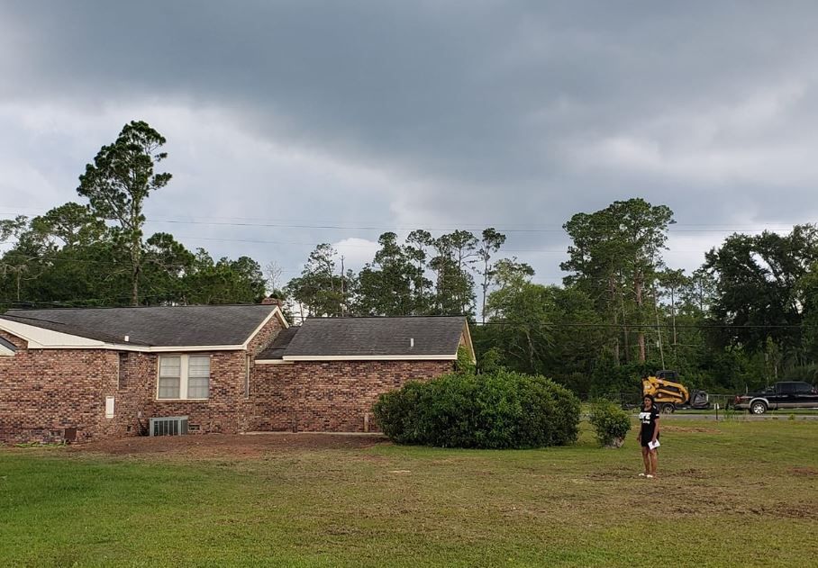A brick house sits in the middle of a lush green field