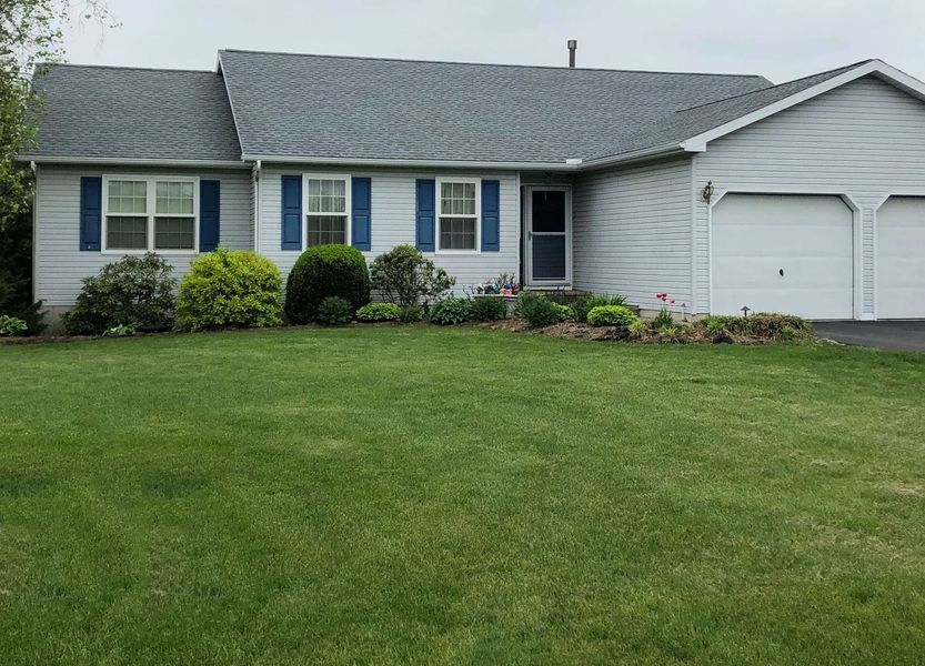 A light blue house with blue shutters, a two-car garage, and a green lawn.