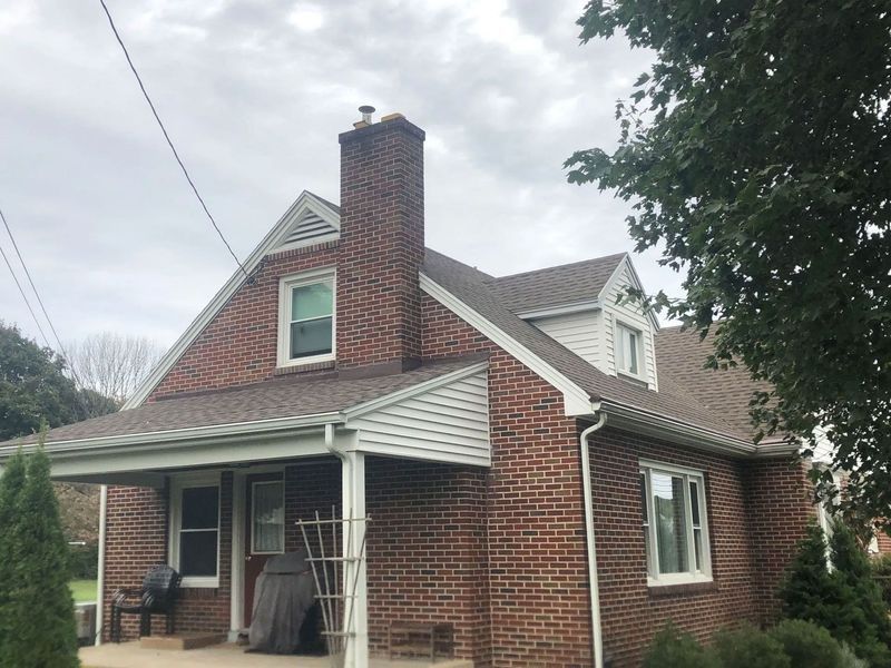 Red brick house with chimney and gabled roof, white trim, and porch.