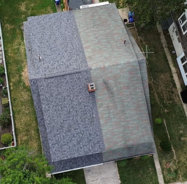 Aerial view of a house with a gray shingle roof and a section of weathered, dark shingles.
