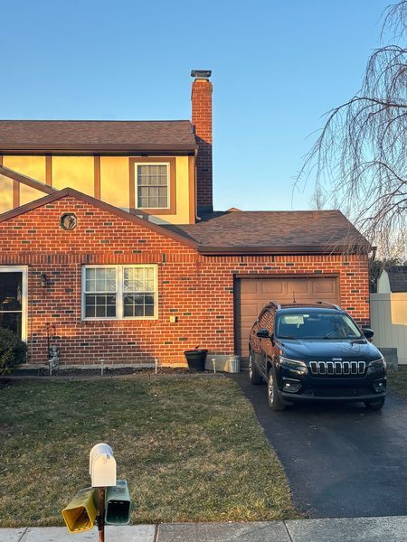 Brick house with a black car parked in the driveway; a mailbox is in the foreground.