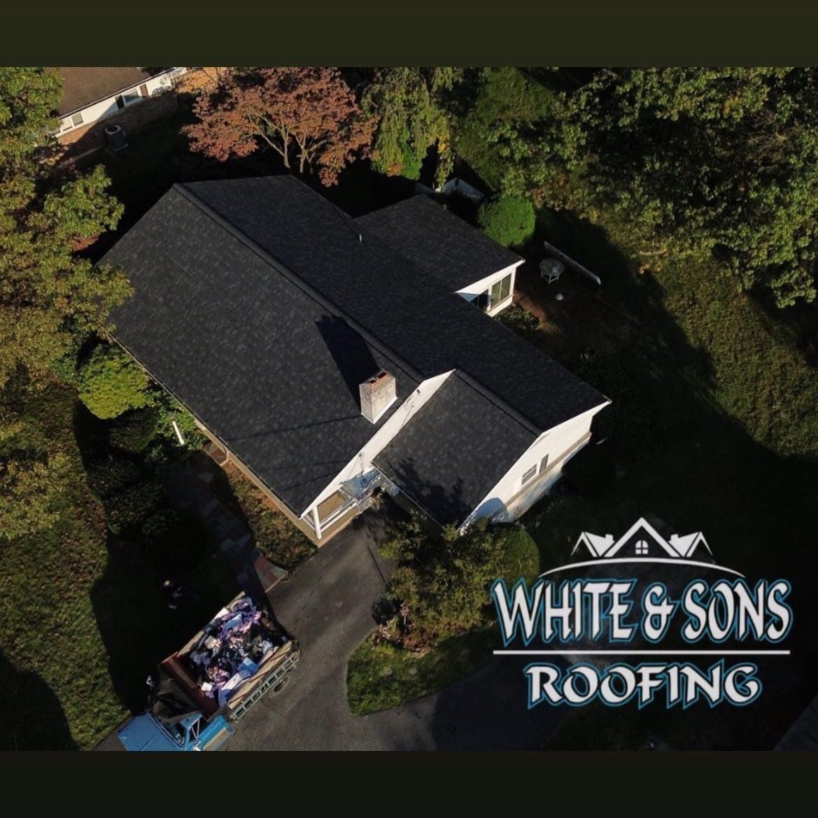 Aerial view of a house with a new black roof by White & Sons Roofing.