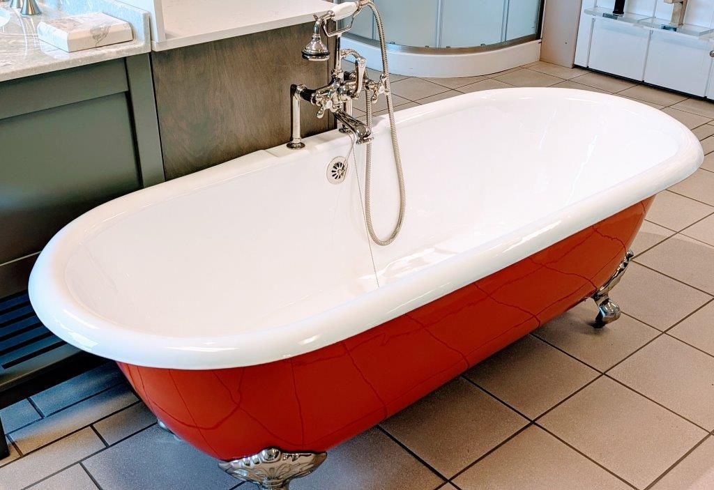 A red and white bathtub is sitting on a tiled floor in a bathroom.