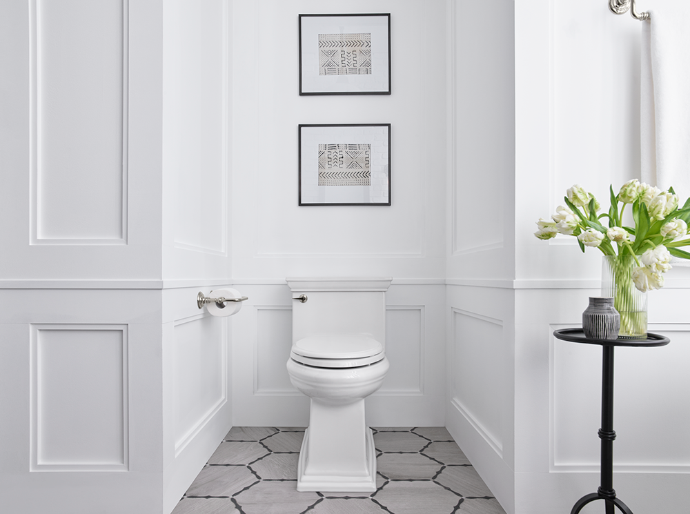 A bathroom with a toilet and a vase of flowers on a table.