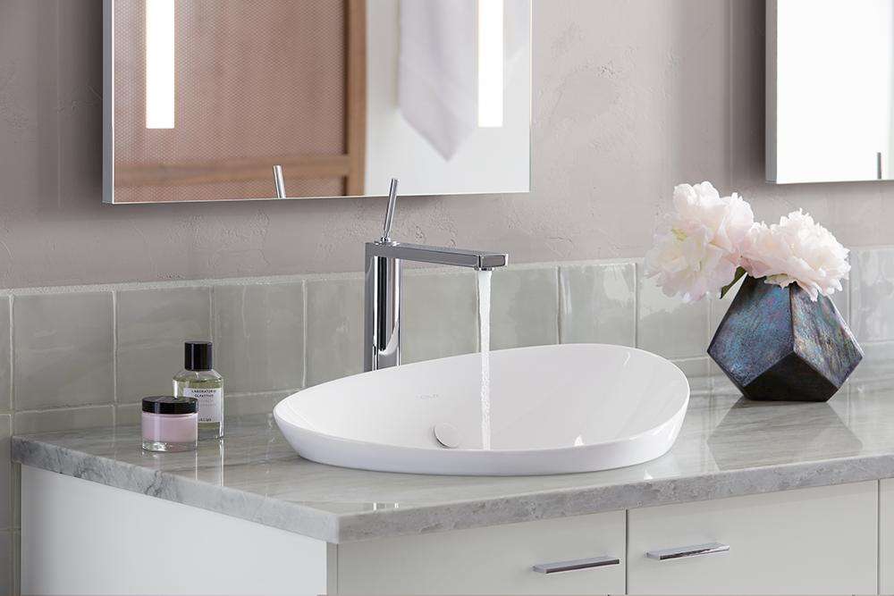 A bathroom with a sink , mirror and vase of flowers.