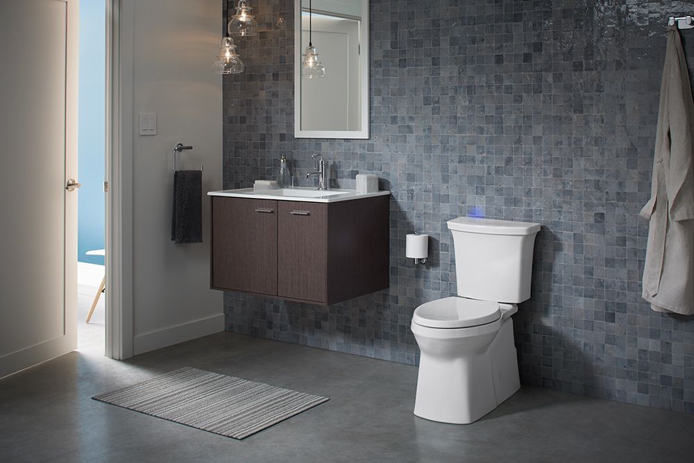A bathroom with a toilet , sink and mirror.