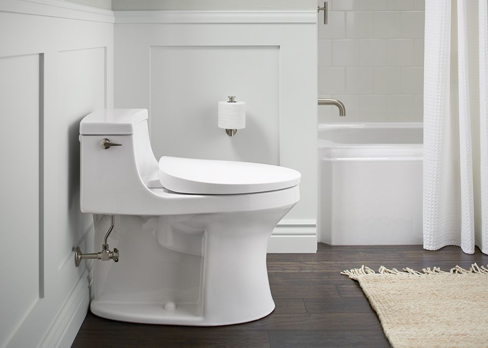 A white toilet is sitting in a bathroom next to a bathtub.