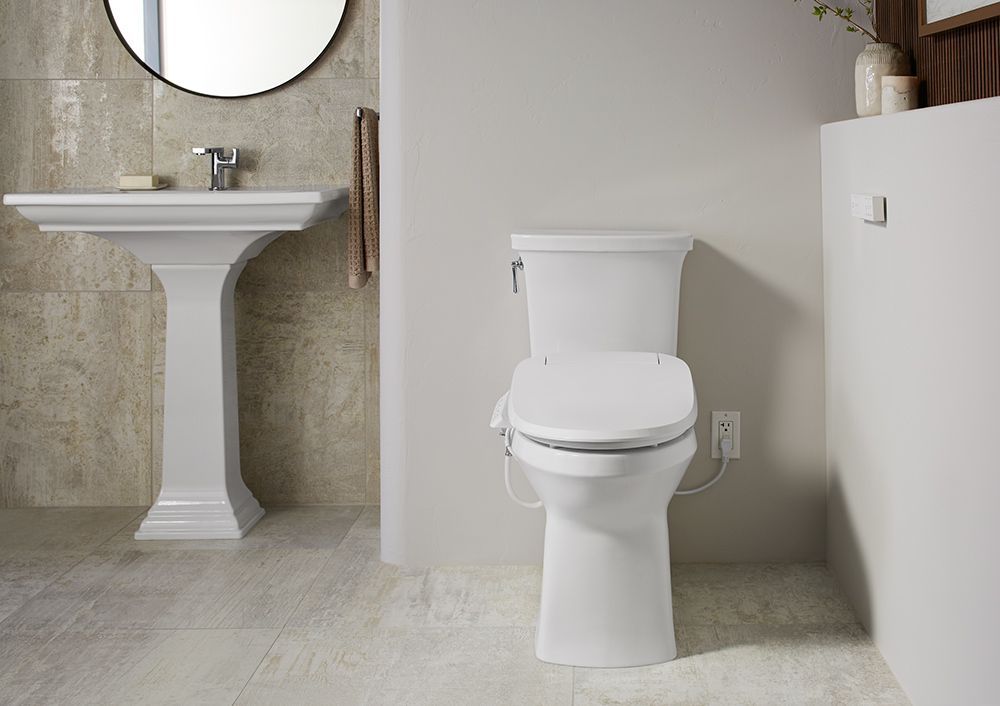 A bathroom with a toilet , sink and mirror.