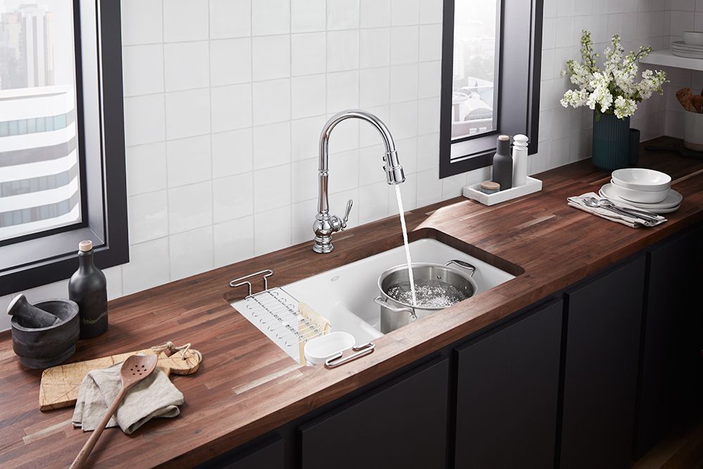 A kitchen sink is sitting on a wooden counter next to a window.