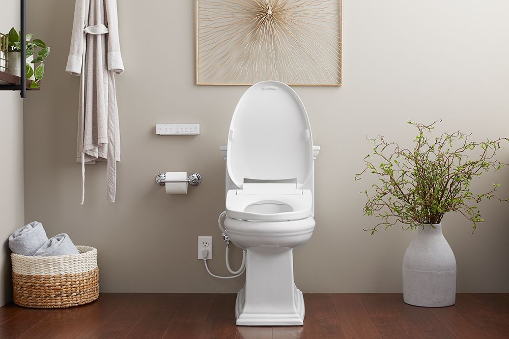 A white toilet is sitting in a bathroom next to a vase of flowers.