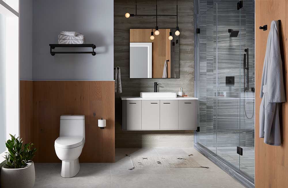 A bathroom with a toilet , sink , mirror and walk in shower.