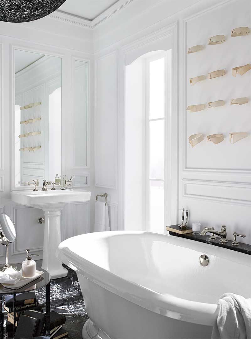 A bathroom with a tub , sink , mirror and window.