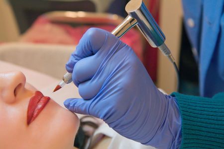 A woman is getting a permanent makeup tattoo on her lips.