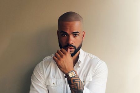 A man with a beard is wearing a white shirt and a watch.