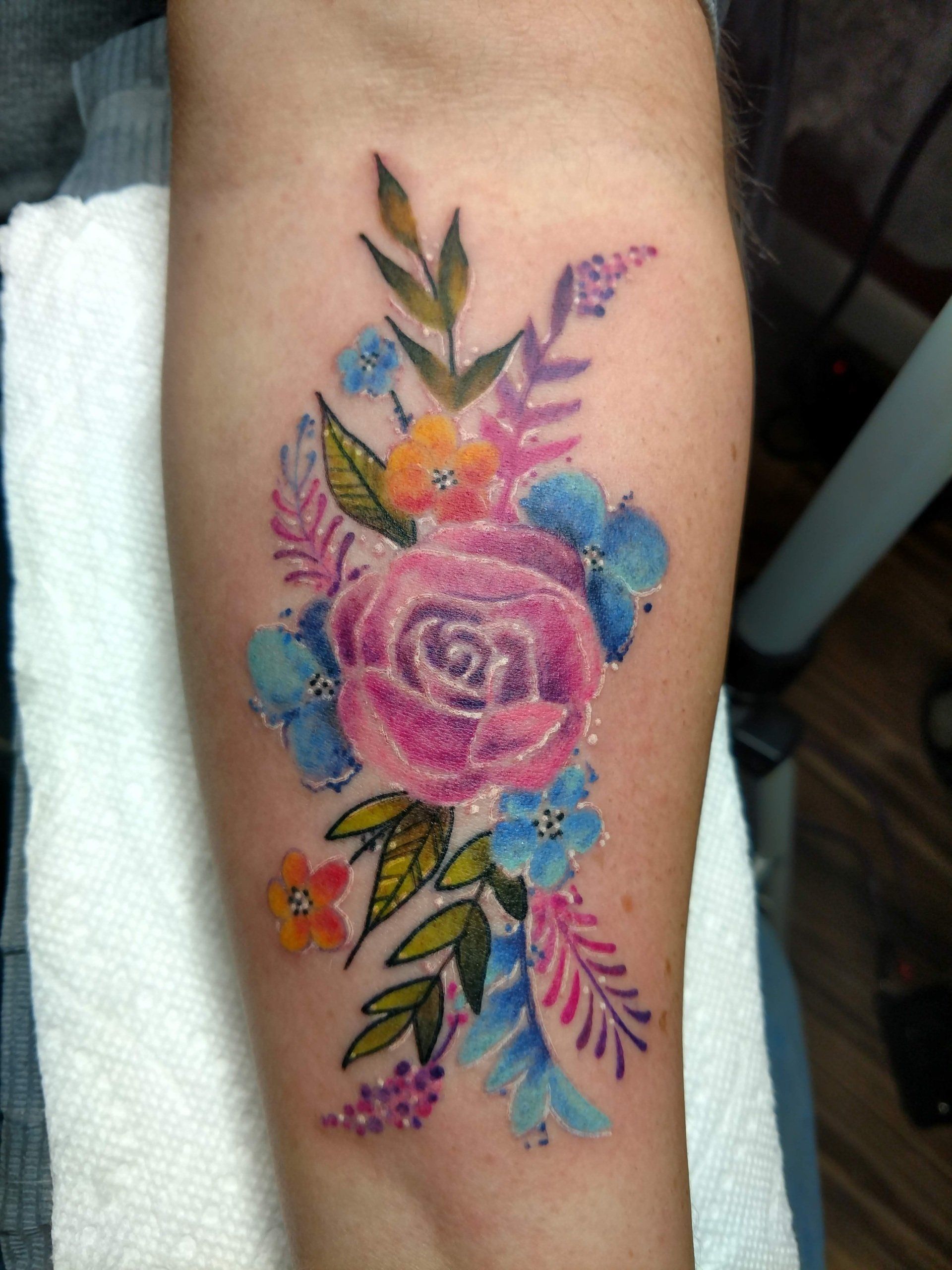 A woman has a tattoo of flowers on her forearm