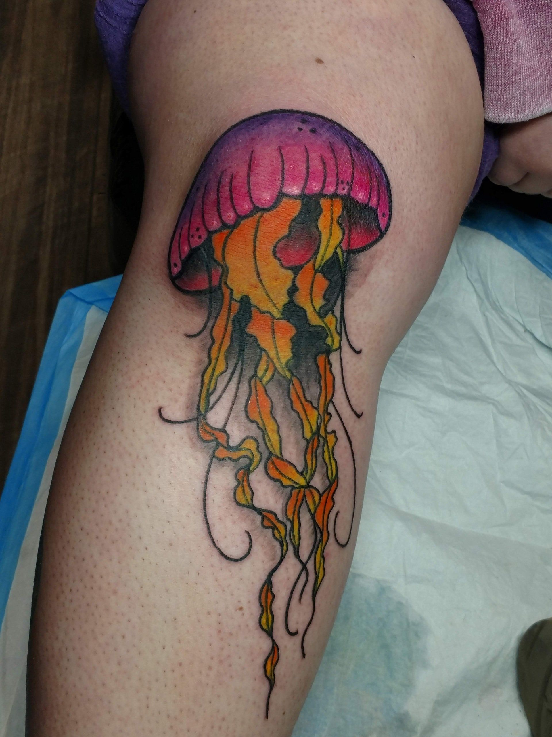 A woman has a tattoo of a jellyfish on her leg