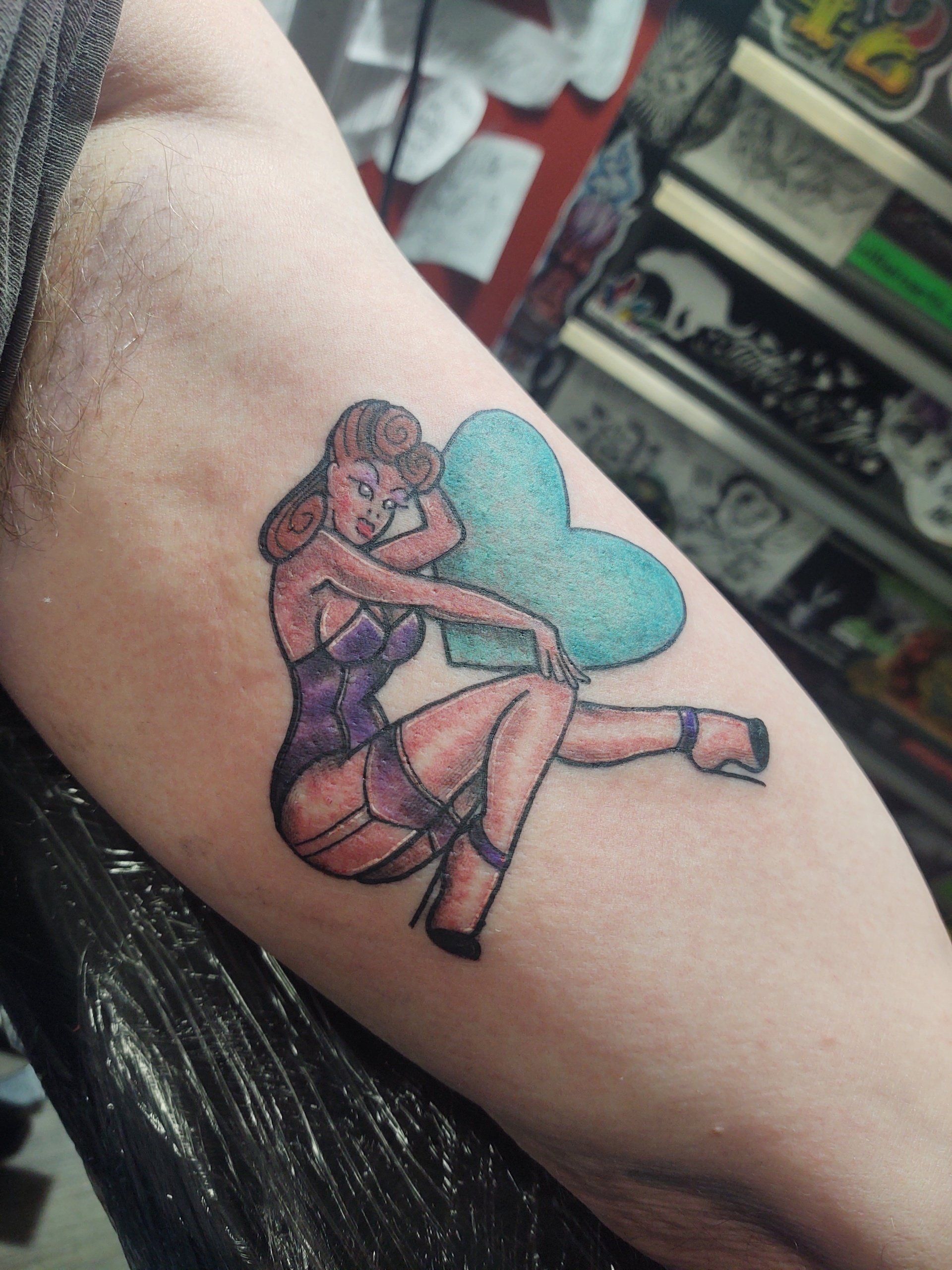 A tattoo of a woman holding a heart on her arm