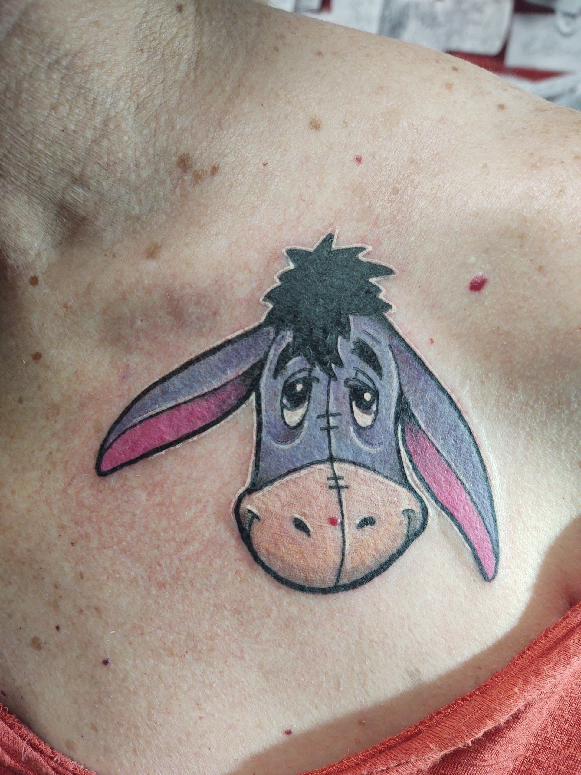 A woman has a tattoo of Eeyore on her chest