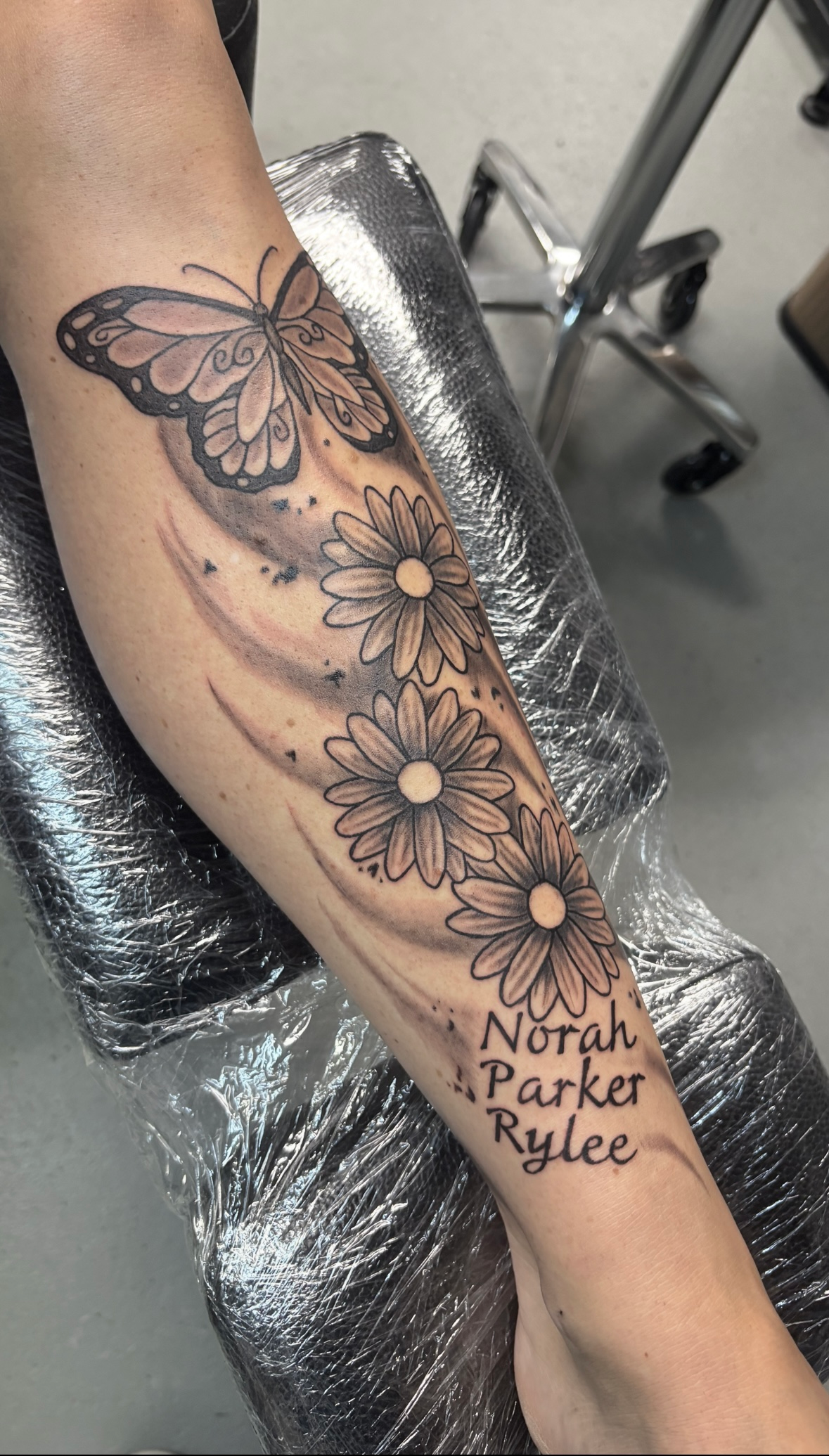 A woman has a tattoo of a butterfly and flowers on her leg.