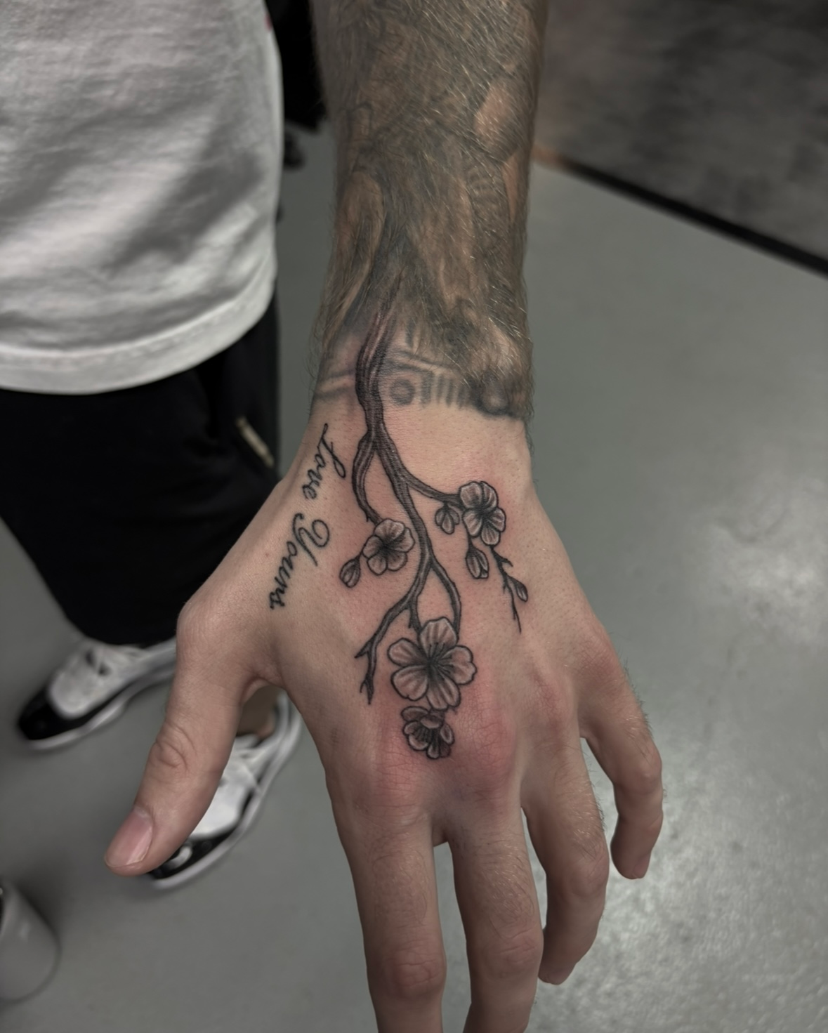 A man has a tattoo of a cherry blossom tree on his hand.