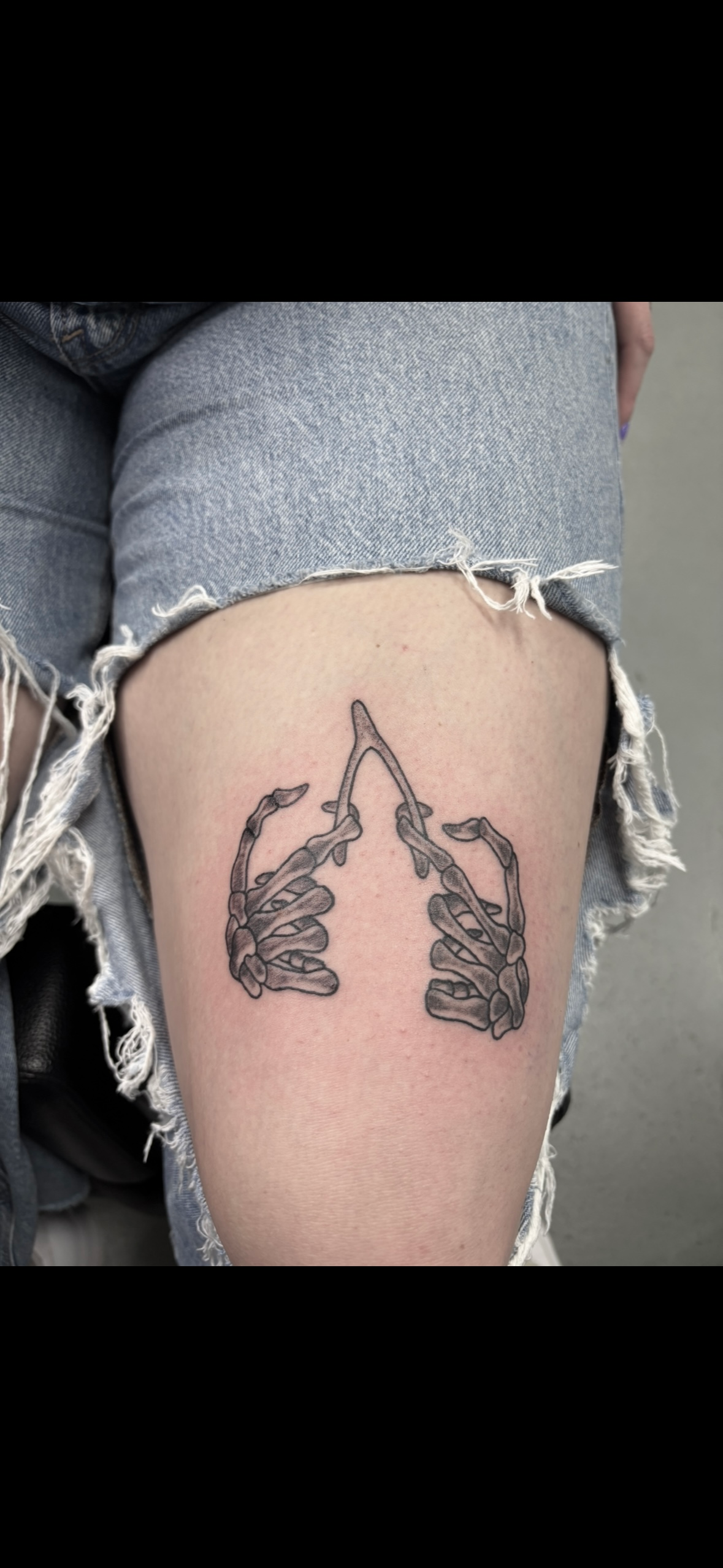 A woman has a tattoo of two hands holding each other on her thigh.