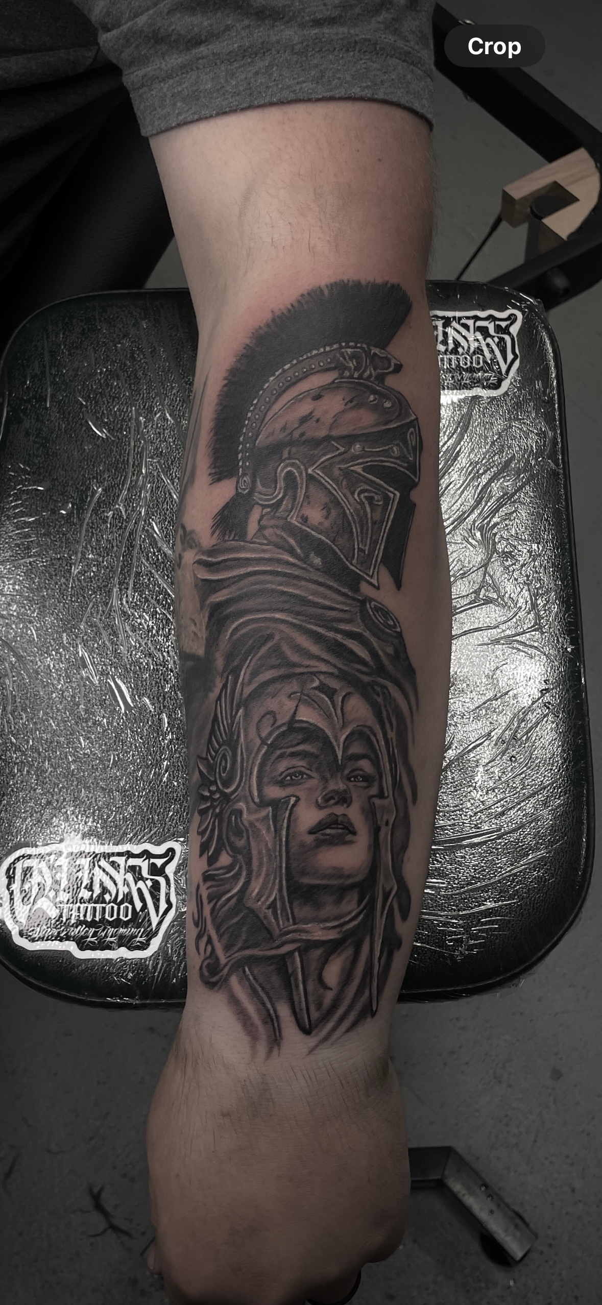 A person with a tattoo on their leg is sitting in a chair.