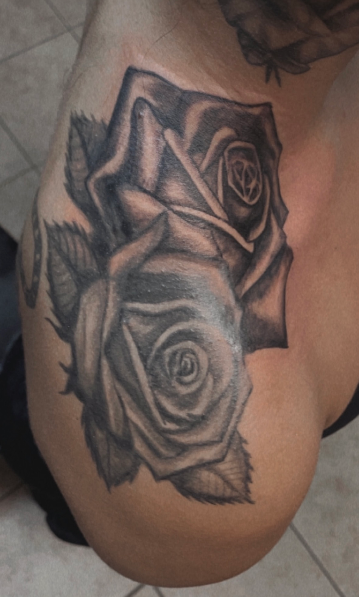 A person has a tattoo of two roses on their shoulder