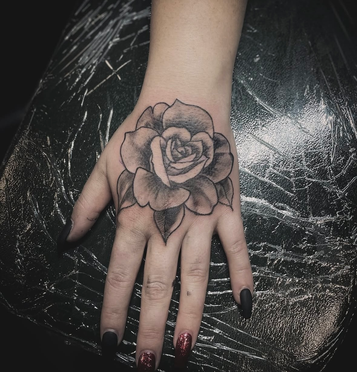 A woman has a tattoo of a rose on her hand