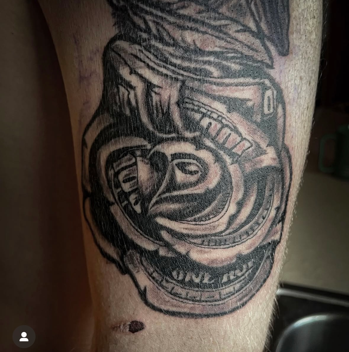 A man has a tattoo of a dollar bill on his leg
