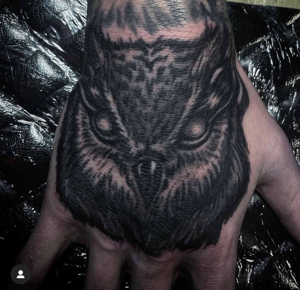 A person has a tattoo of an owl on their hand