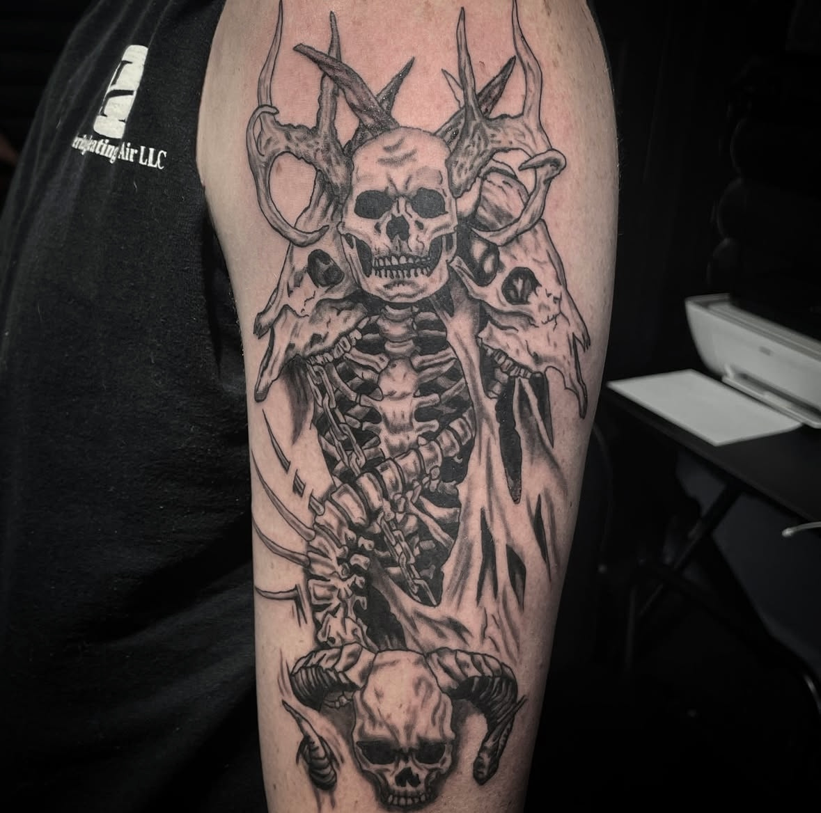 A man has a tattoo of a skeleton with horns on his arm