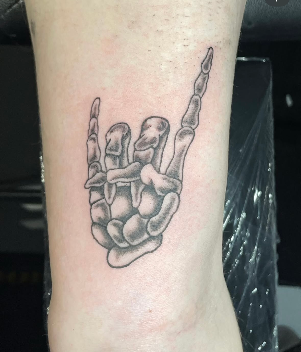 A tattoo of a skeleton hand on a person 's ankle