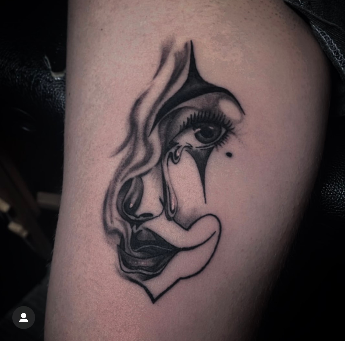 A black and white tattoo of a woman 's face with a tear coming out of her eye