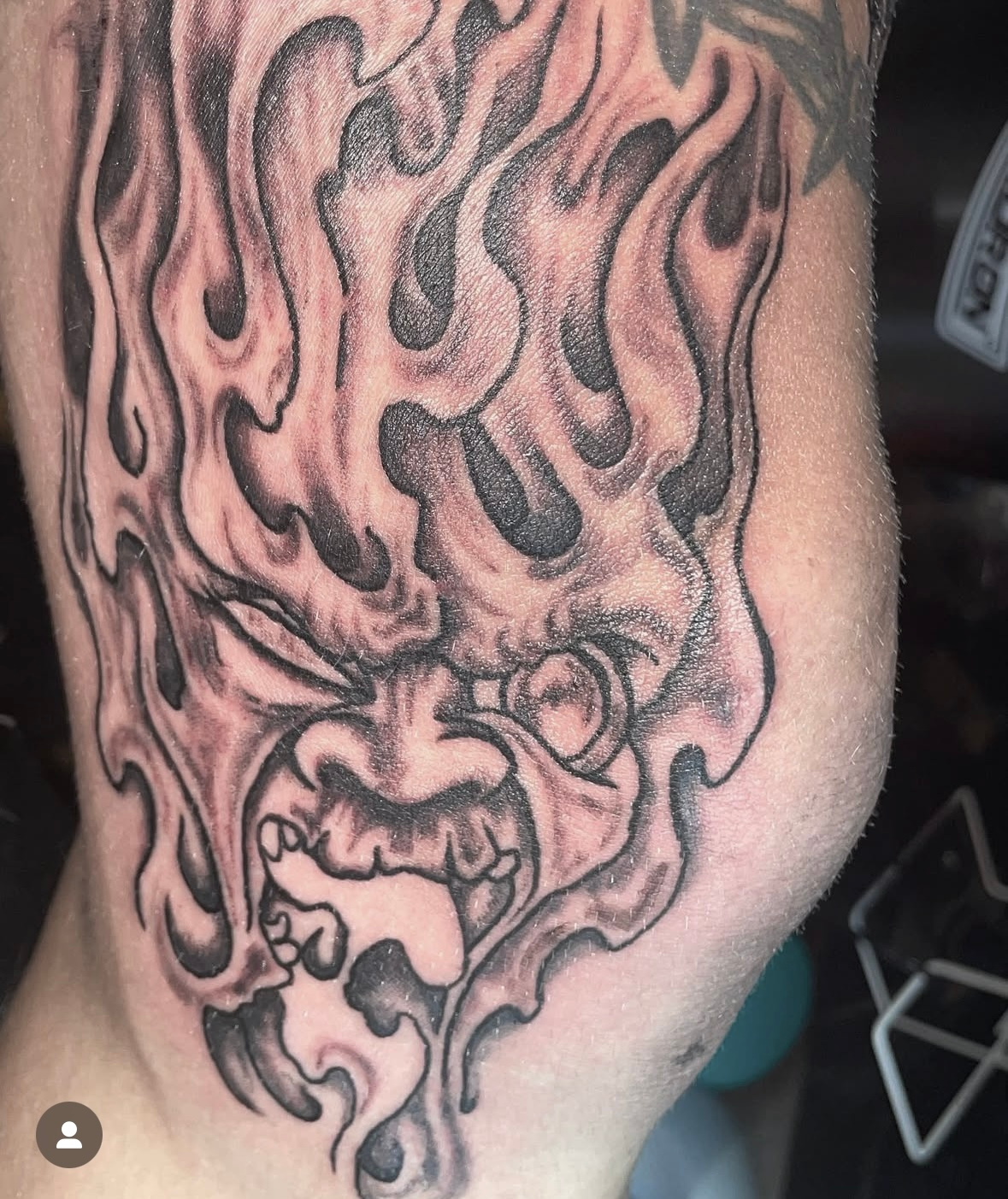 A tattoo of a face with flames on it
