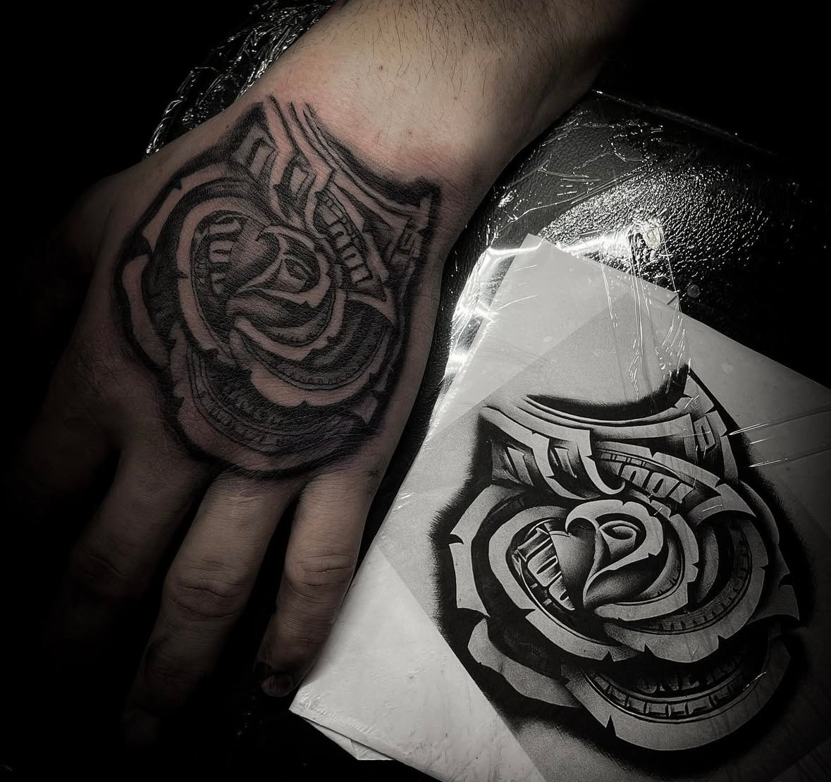 A black and white tattoo of a rose on a person 's hand