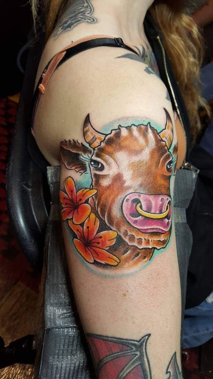 A woman has a tattoo of a cow and flowers on her arm