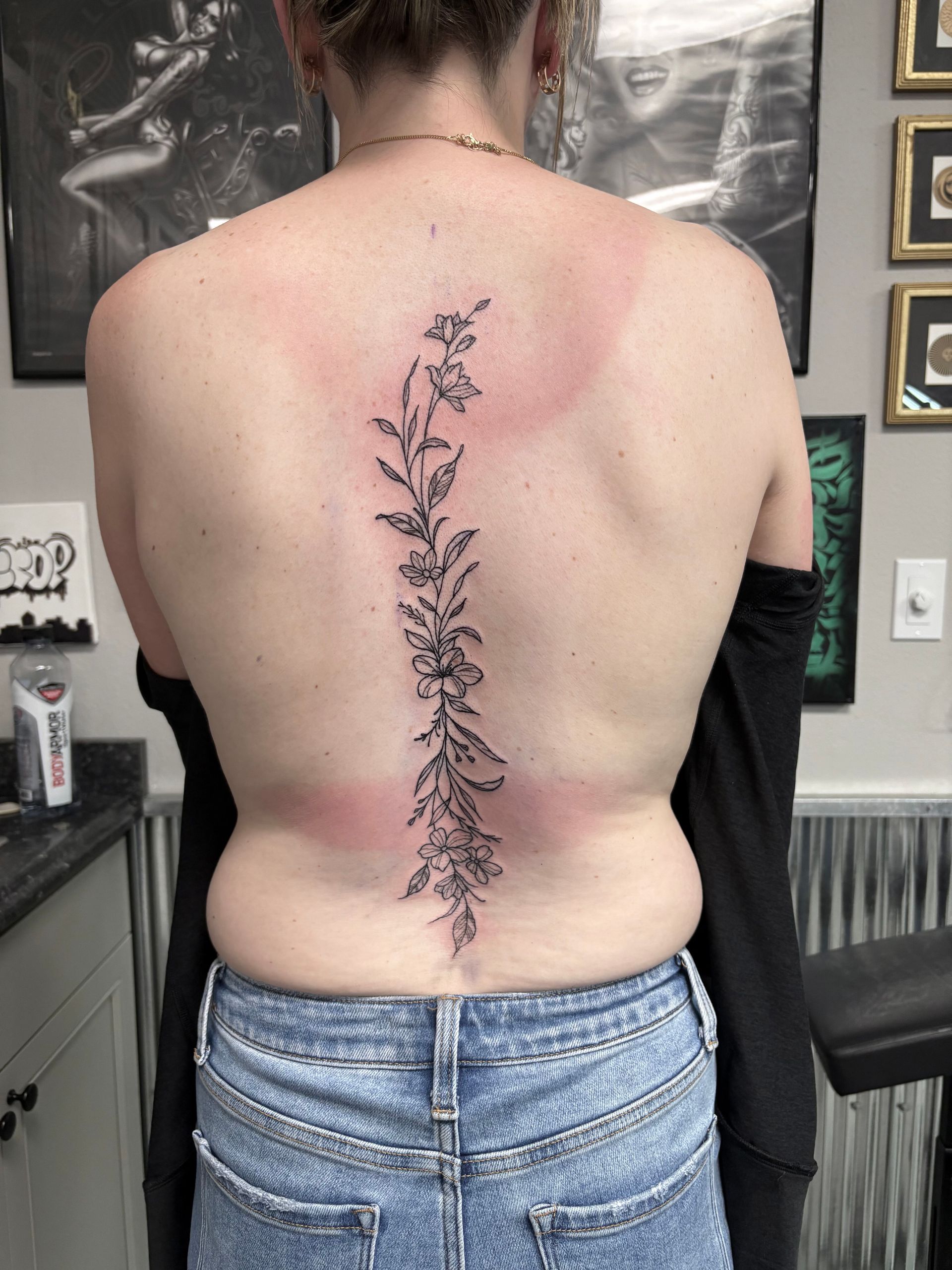 A woman has a tattoo of flowers on her back