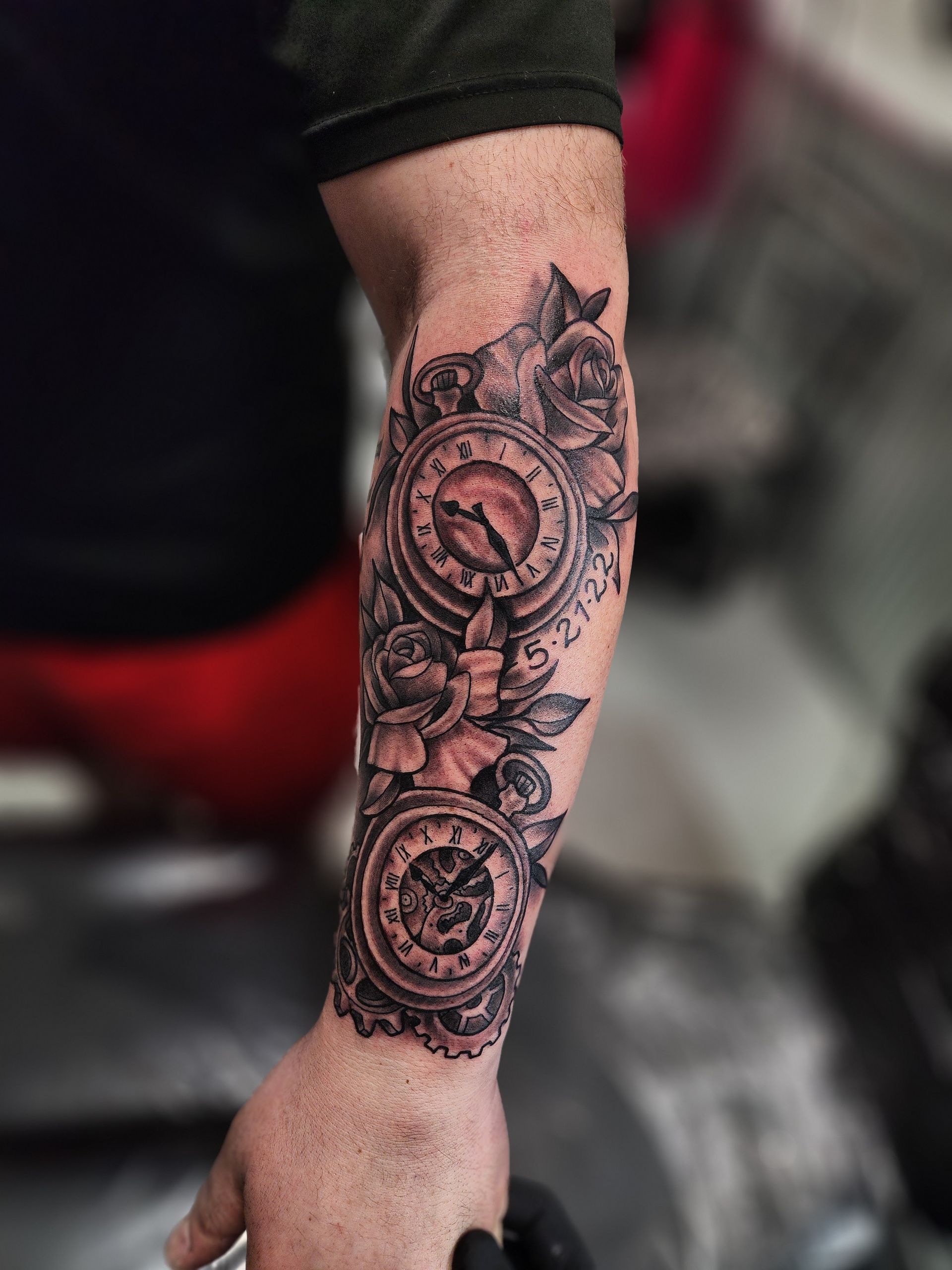 Black and gray forearm tattoo: pocket watches with floral elements.