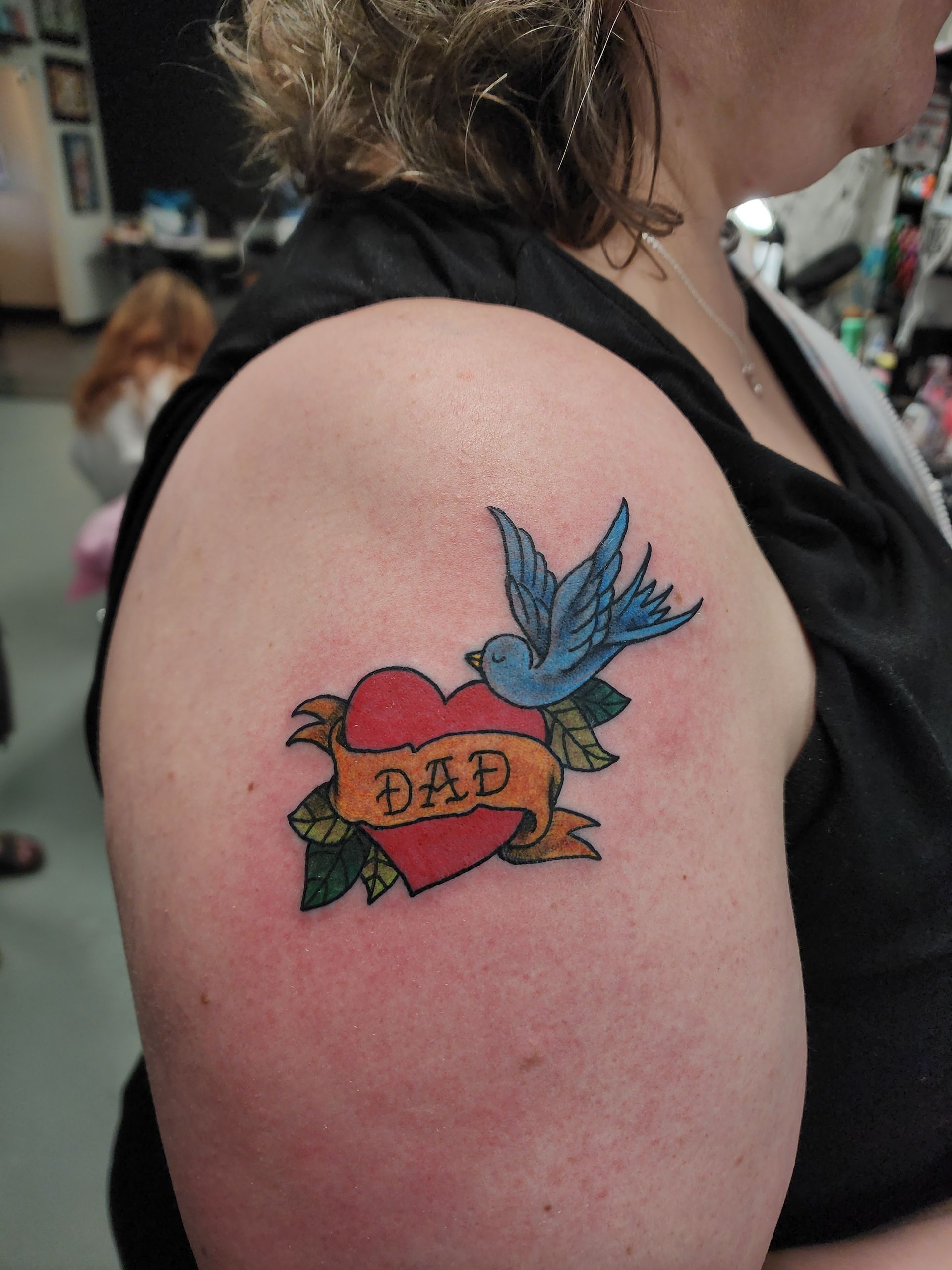 Tattoo on woman's arm of a red heart with a