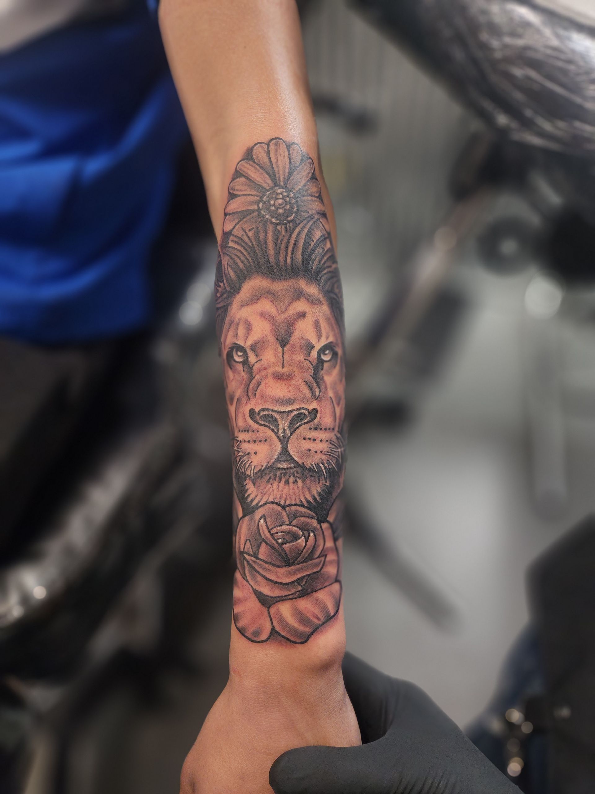 Lion tattoo on a forearm, featuring a detailed face and a rose.