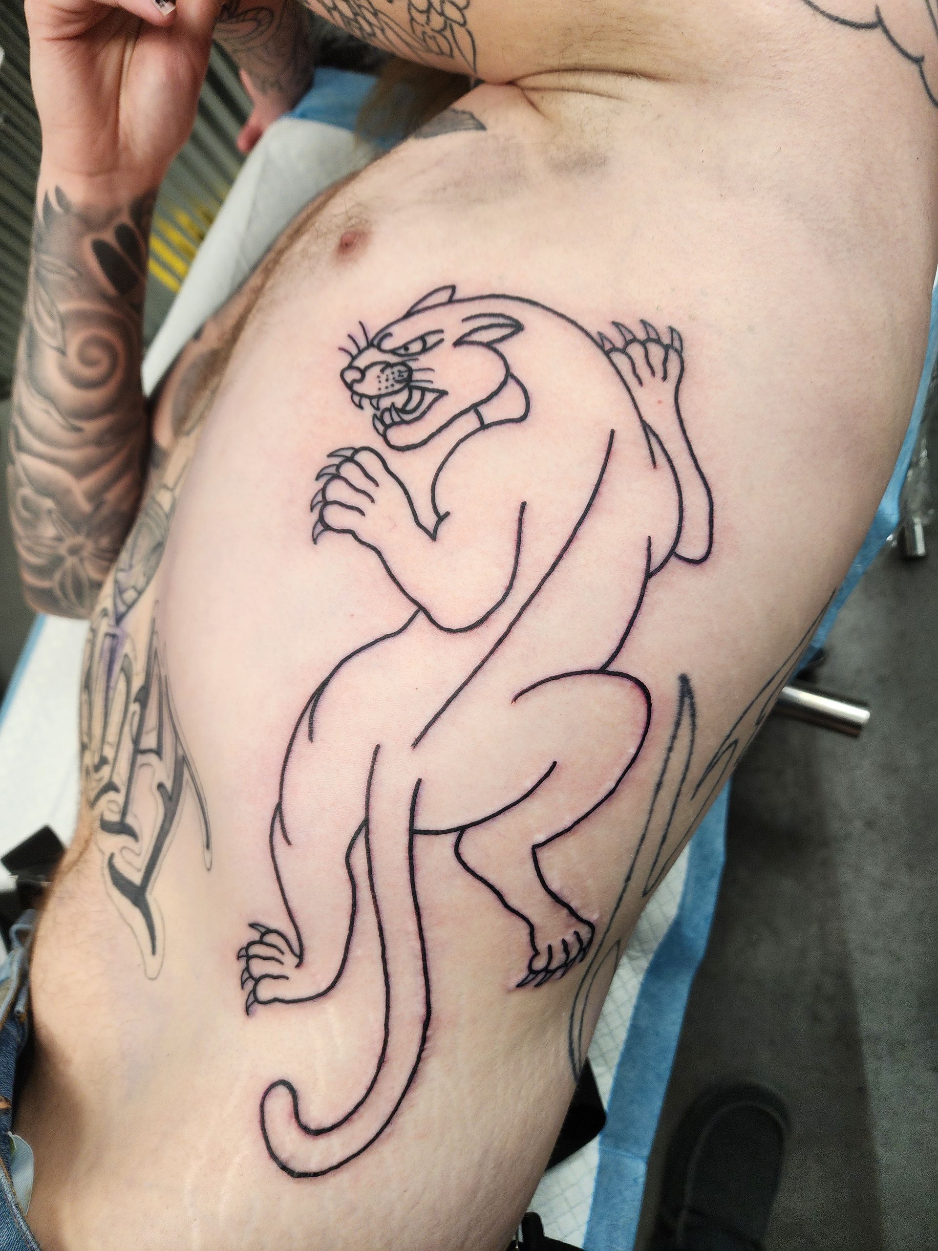Line drawing of a panther tattoo on a person's torso. The panther is crouching, claws out.