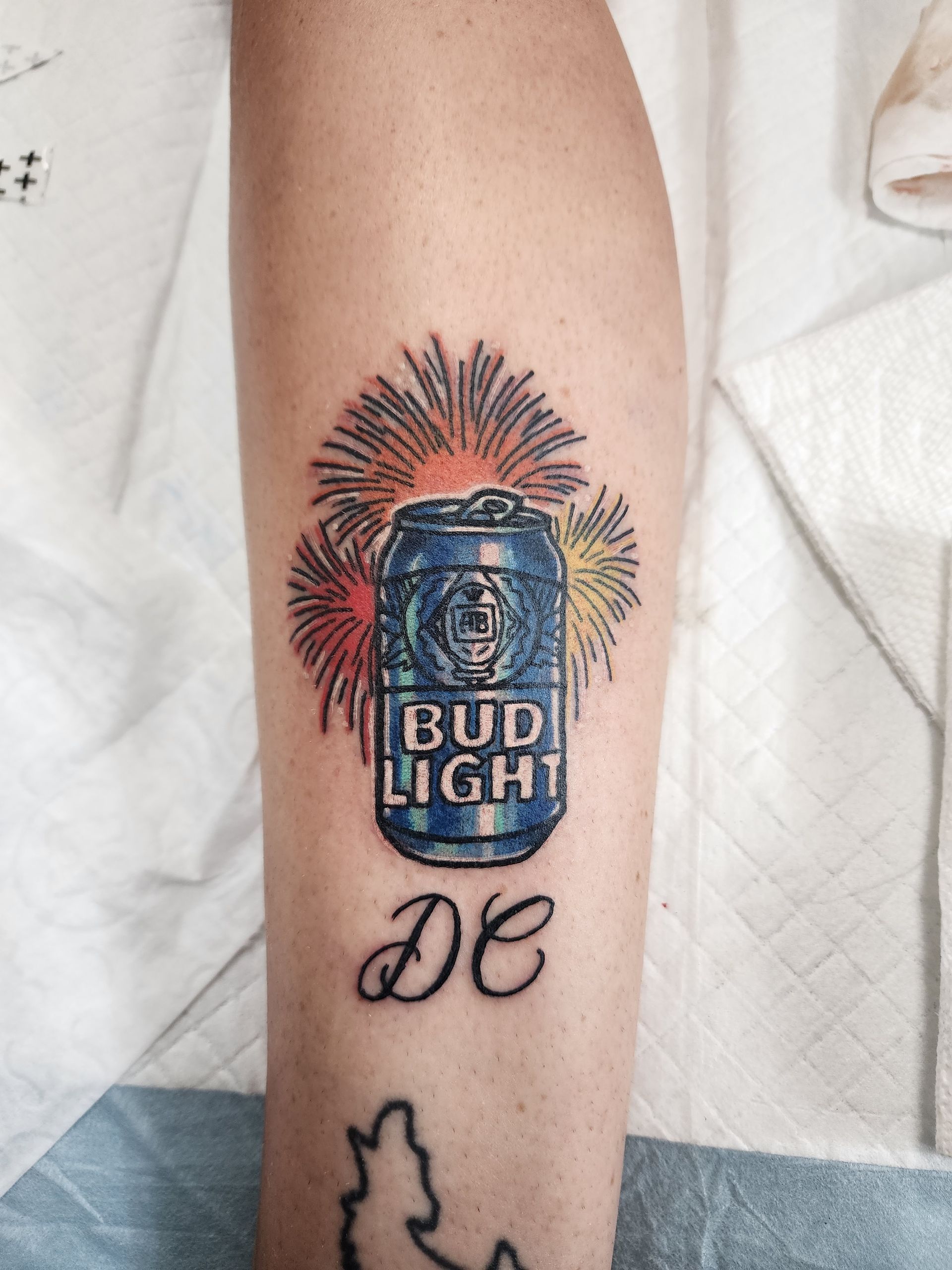 Tattoo of a Bud Light can with fireworks in the background and