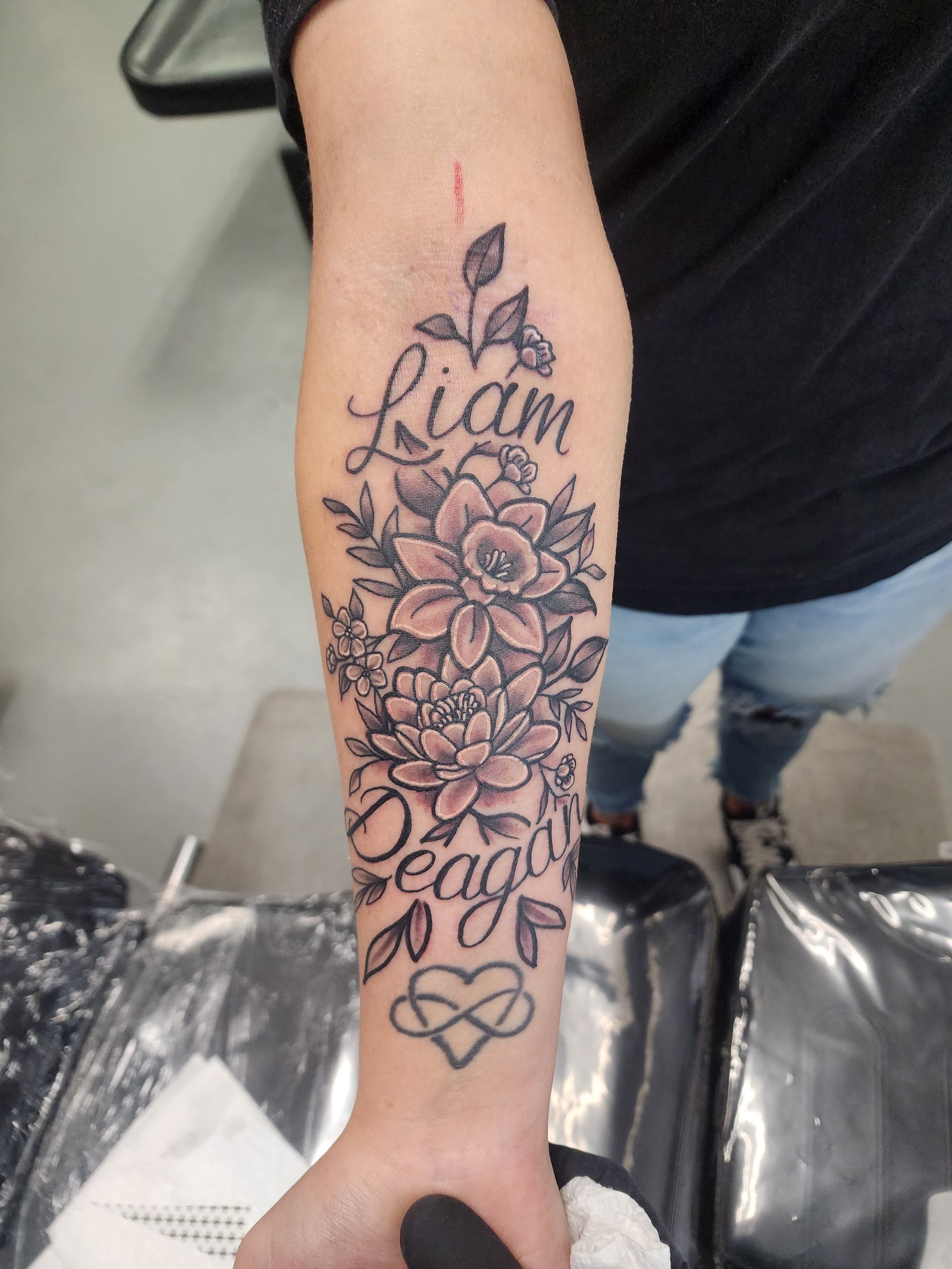Arm tattoo with floral design, names