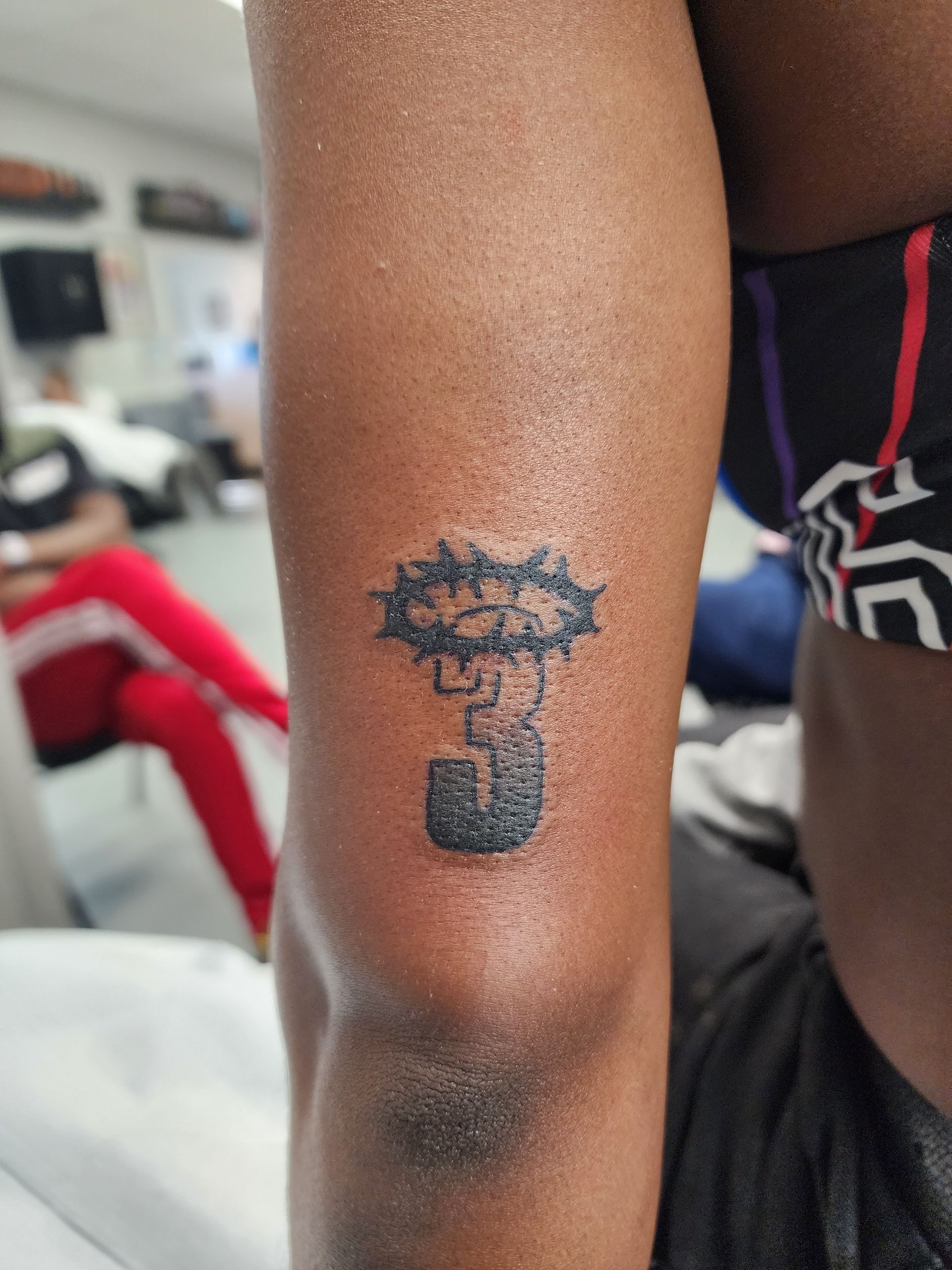 Tattoo on arm depicting a stylized explosion shape over an abstract object; close-up view.